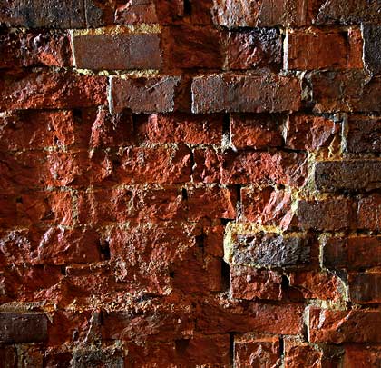 In close-up: a section of brickwork where the faces have been lost.