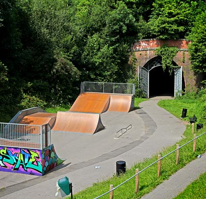 A skateboard park occupies the trackbed beyond the tunnel mouth.